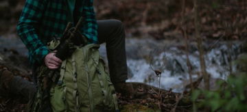 a man sitting on the ground in the woods